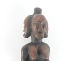 statue of a woman sitting on a stool with her hands on her chest