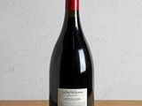 a bottle of red wine sitting on a wooden table