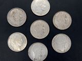six different british silver coins on a black surface