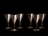 quatre verres à vin sont alignés sur un fond noir