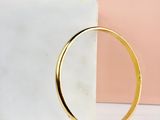 a close up of a gold bang bracelet on a marble block