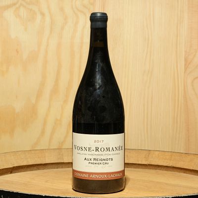 a bottle of wine sitting on top of a wooden barrel