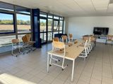 des tables et des chaises dans une pièce dotée de grandes fenêtres et d'une télévision à écran plat