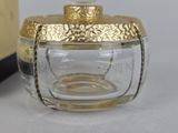 a glass jar with a gold lid next to a bottle