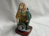 figurine représentant un homme assis sur un bloc de bois