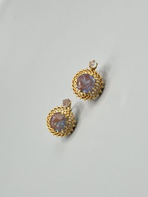 une paire de boucles d'oreilles en or ornées de pierres violettes sur un fond blanc