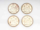 four different types of coins are shown on a white surface