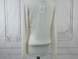 the white sweater is on a mannequin stand in front of a white wall