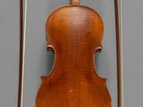 an old violin with a bow and bow rest on a gray surface
