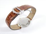 a watch that is sitting on top of a brown strap