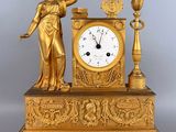 a gold clock with a statue of a woman holding a harp