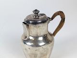 une théière ancienne en argent avec une anse en bois, sur fond blanc
