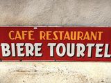 une enseigne rouge sur laquelle on peut lire « Café-restaurant Béré Tourtel »