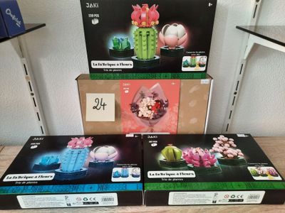 Trois boîtes contenant différentes sortes de fleurs sont posées sur une table.