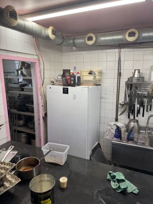 une cuisine équipée d'un réfrigérateur, d'une cuisinière, d'un évier et d'autres éléments posés sur le plan de travail