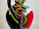 un vase coloré posé sur un socle noir, sur fond blanc