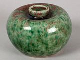 un vase vert et rouge avec un socle blanc
