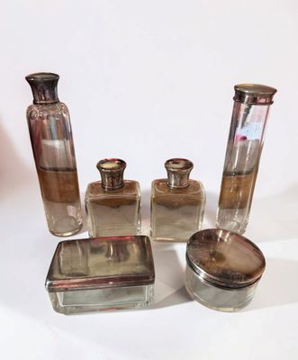 four glass bottles and a silver container on a white surface