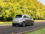 a small silver car driving down the road in front of some trees