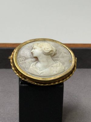 un gros plan sur une bague blanche et dorée ornée d'un visage de femme