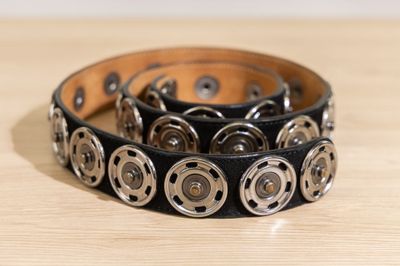 bracelet en cuir noir orné de clous métalliques sur un support en bois