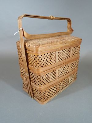 une image représentant un panier en osier muni d'anses, sur fond gris