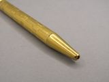 an image of a gold colored pen on a gray surface