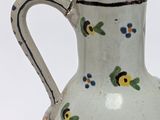 a small white vase with blue and yellow flowers on it