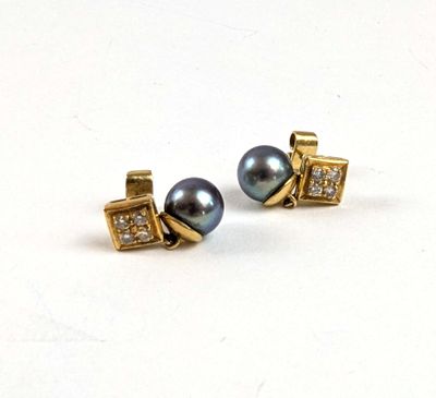 une paire de boucles d'oreilles en perles noires et diamants posées sur une surface blanche
