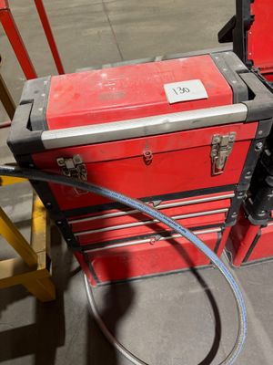une boîte à outils rouge à laquelle est fixé un tuyau