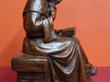 statue d'une femme assise sur un banc en train de lire un livre
