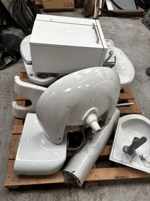 une pile de cuvettes de WC et un lavabo posés sur une palette