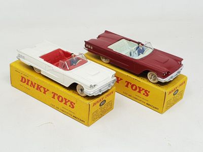 two toy cars sitting on top of boxes on a white surface