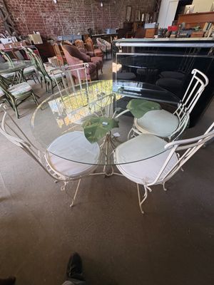 une table en verre avec quatre chaises et un vase posé dessus