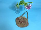 a small purse sitting next to a vase with a flower in it