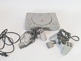 a video game console and two controllers on a white table