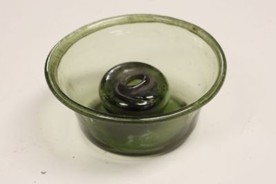 a green glass cup with a black lid on a white table