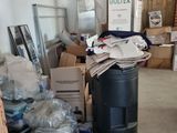 a trash can in the middle of a room filled with boxes and other items