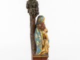 a statue of a man sitting under a tree with a bird on his shoulder