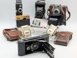 many different types of cameras sitting on a white surface