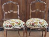 pair of antique chairs with floral upholstered seats in front of wooden doors