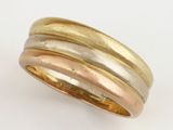 three bands of gold and silver ring on a white surface