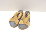 pair of yellow sandals on a white surface with a white wall in the background