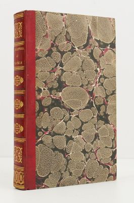 un vieux livre à la couverture rouge posé sur une table blanche