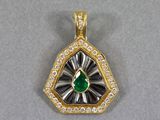 un gros plan d'un pendentif en forme de diamant vert et blanc posé sur une surface grise