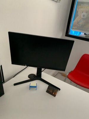 un écran d'ordinateur posé sur un bureau à côté d'une chaise rouge
