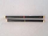 pair of two black and gold colored chopsticks on a white surface