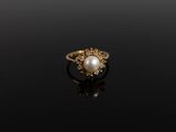 une image représentant une bague en or sertie d'une perle, sur un fond noir