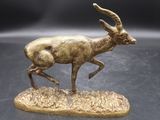 statue en bronze représentant une gazelle courant sur un rocher posé sur un fond noir