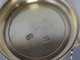 an antique silver plate with a handle on a stand